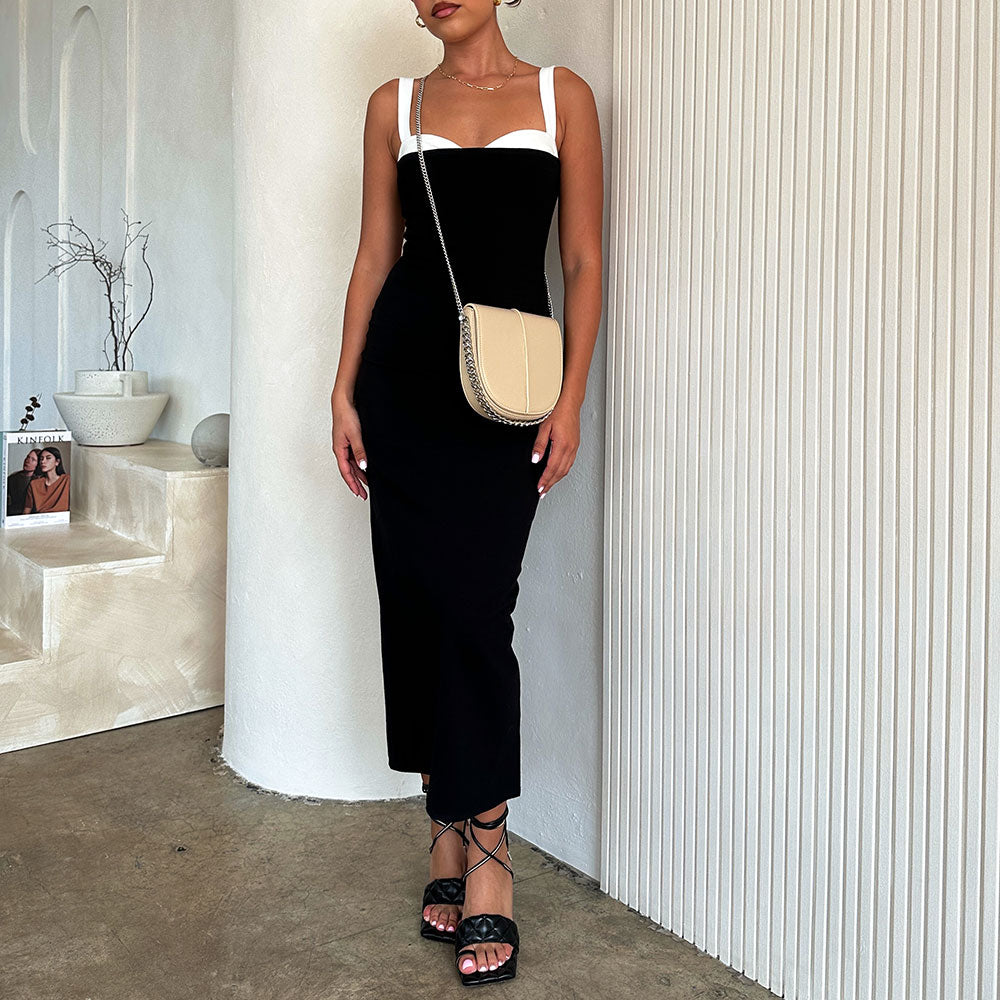 A model holding a nude vegan leather crossbody handbag against a white wall.