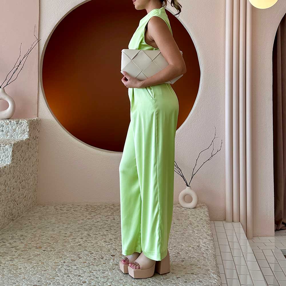 A model wearing a small bone woven vegan leather clutch with a crossbody strap.