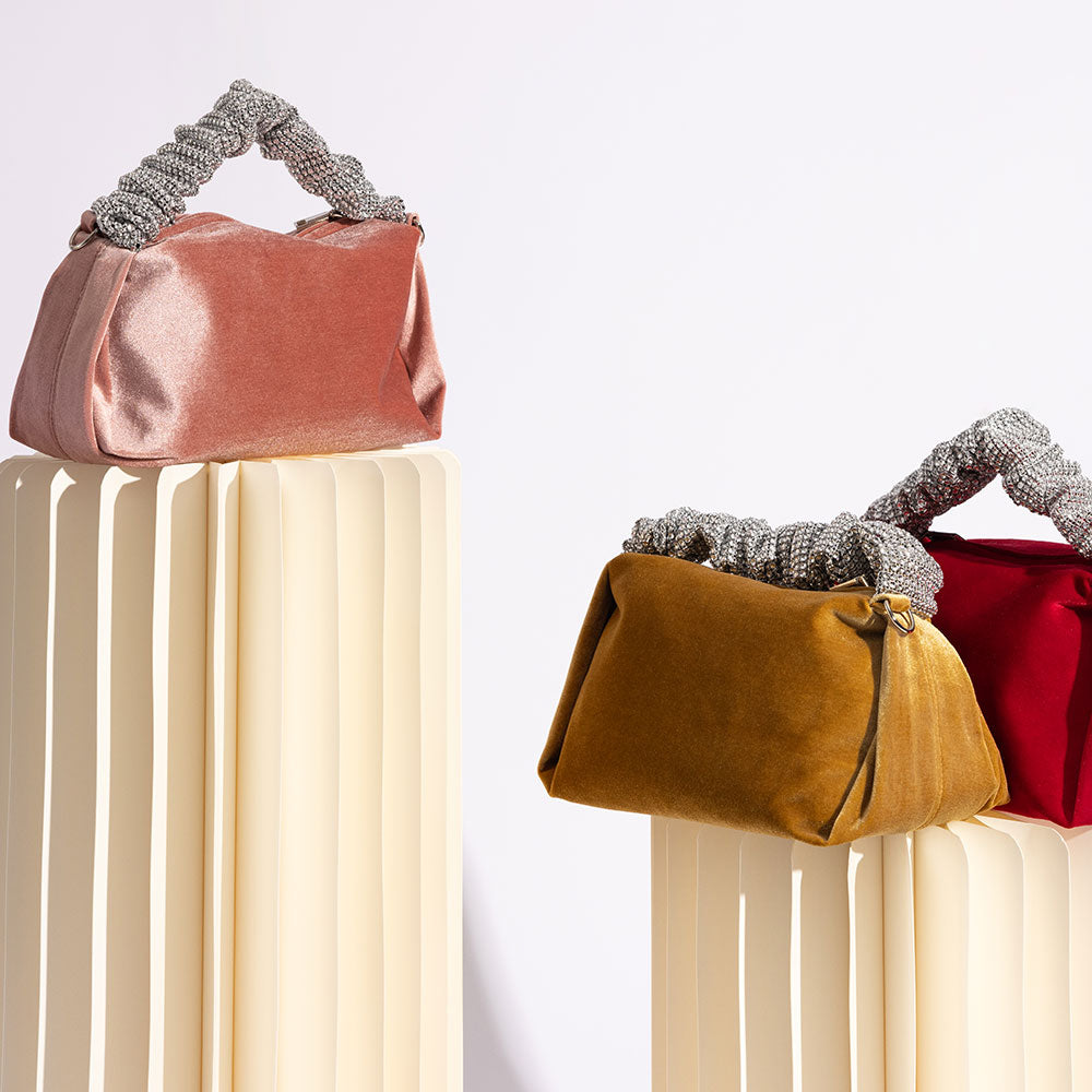 A still image of three velvet top handle bags with silver encrusted handle against a white background. 