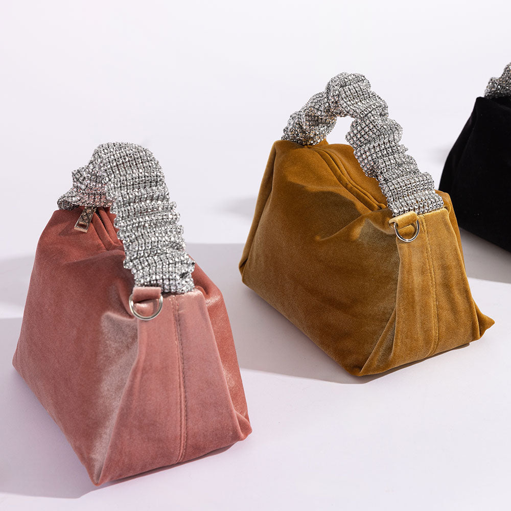 A still image of three velvet top handle bags with silver encrusted handles against a white background. 