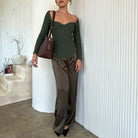 Model wearing an espresso recycled vegan leather shoulder bag against a white wall. 