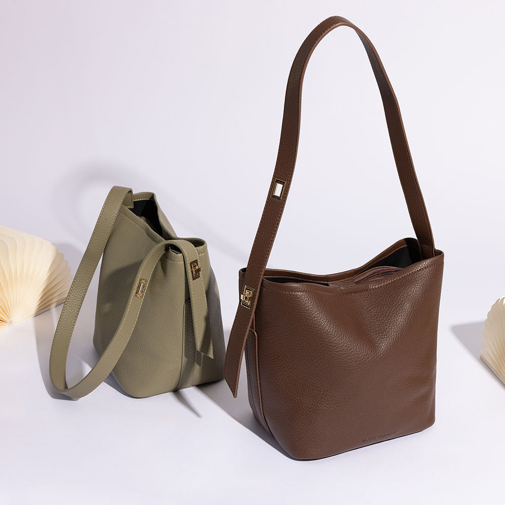 A still image of two recycled vegan leather shoulder bag with adjustable strap against a white wall. 