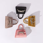 A still image of four mini velvet top handle bags with a silver encrusted bows against a white background,