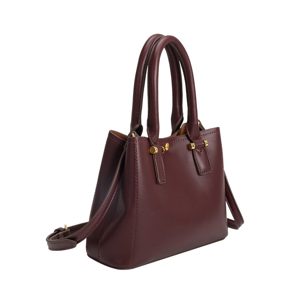 A small burgundy recycled vegan leather crossbody handbag with gold hardware. 