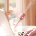 Pink portable mini humidifier in a cup of water