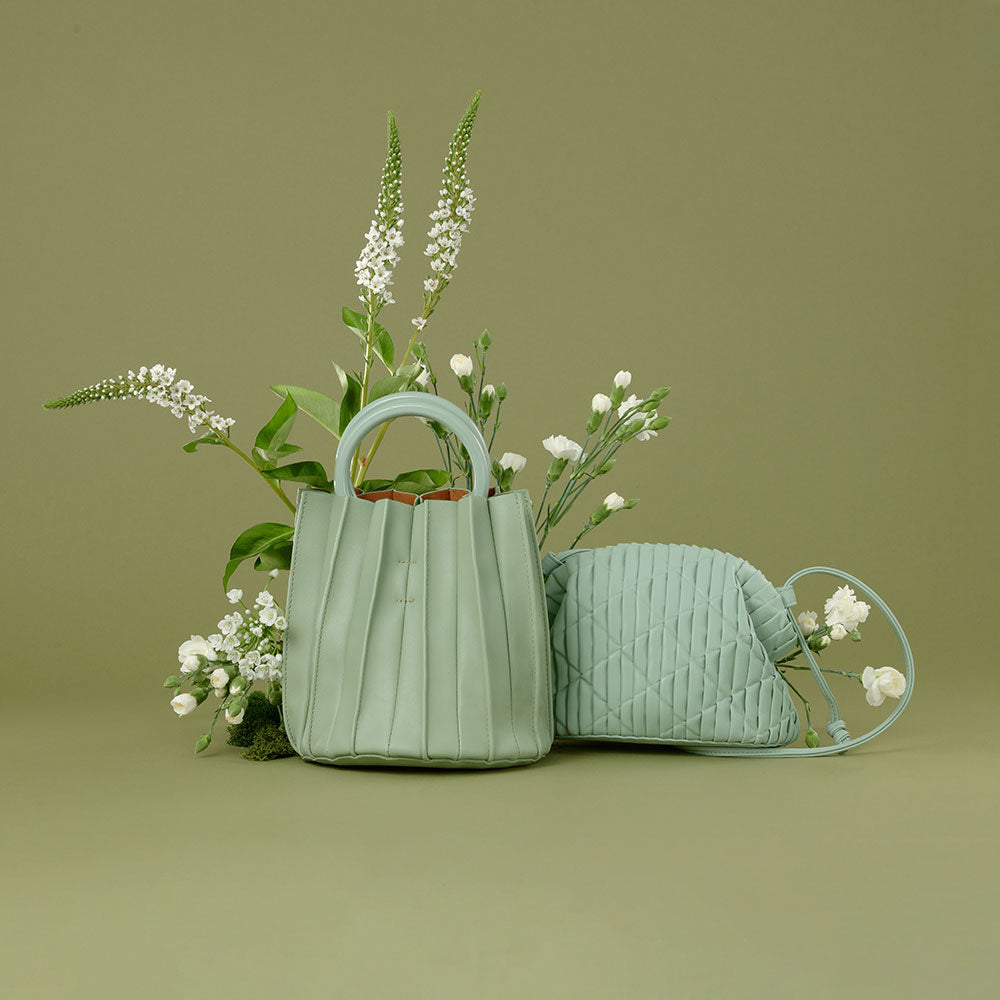 A still image of A small mint accordion pleated drawstring top handle bag.