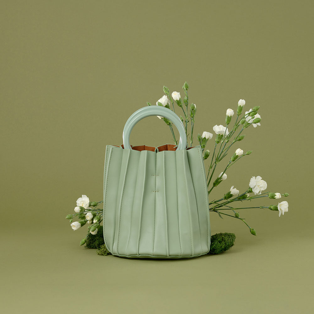 A still image of A small mint accordion pleated drawstring top handle bag.
